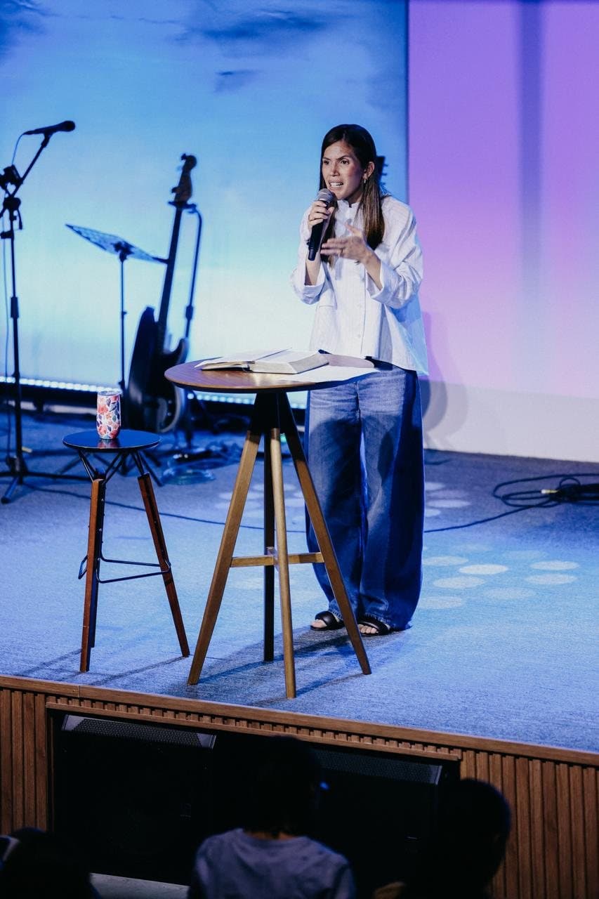 Nina Hayashi ministrando com microfone no palco de uma igreja