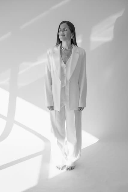 Nina Hayashi de terno branco, em pé, sob luz natural